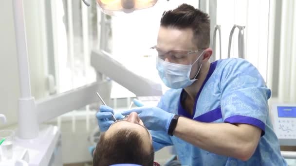 Dentista perforando dientes de pacientes en la clínica — Vídeos de Stock