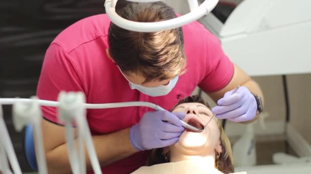 Mannelijke tandarts behandelt tanden patiënt meisje — Stockvideo