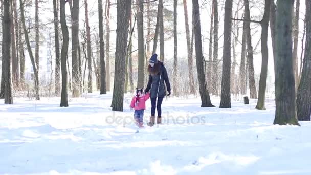 Мать и ее маленькая дочь прогуливаются по заснеженным лесам — стоковое видео