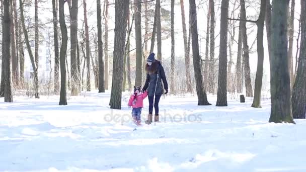 Anne ve küçük kızı karlı ormanda yürüyüş — Stok video