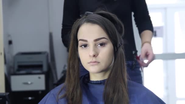 Cabeleireiro feminino de pé e fazendo penteado para linda jovem mulher no salão de beleza — Vídeo de Stock