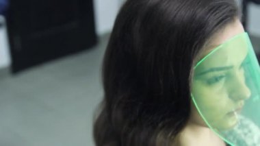 Kuaför Güzellik Salonu saç şekillendirme yapar. Modeli koruyucu maske yüzünü kaplayan