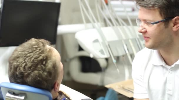 Le dentiste principal communique avec le patient et examine la cavité buccale — Video