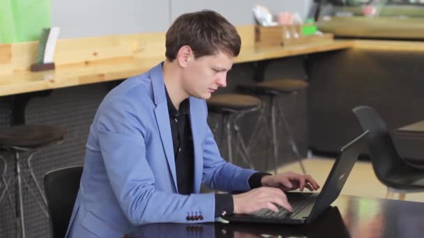 Молодий бізнесмен працює на комп'ютері в кафе — стокове відео