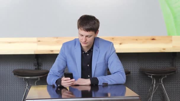 A young man uses his mobile device in a cafe — Stock Video