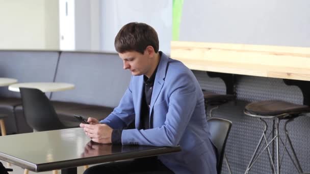 A young man uses his mobile device in a cafe — Stock Video