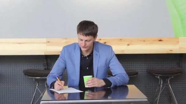 Mladý podnikatel zapíše podnikatelský plán v kavárně — Stock video