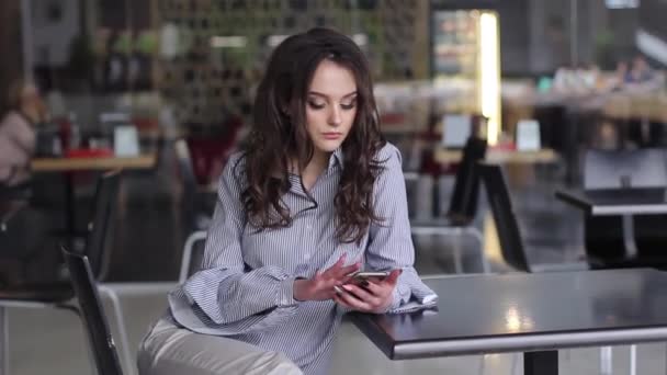 Hermosa joven mientras que en la cafetería utiliza su dispositivo móvil — Vídeo de stock