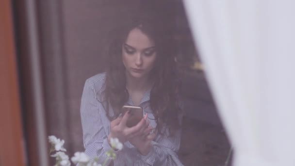 Menina bonita em um café usa o telefone para discar a mensagem de texto — Vídeo de Stock