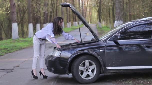 Atraente jovem mulher olhando sob o capô do carro — Vídeo de Stock