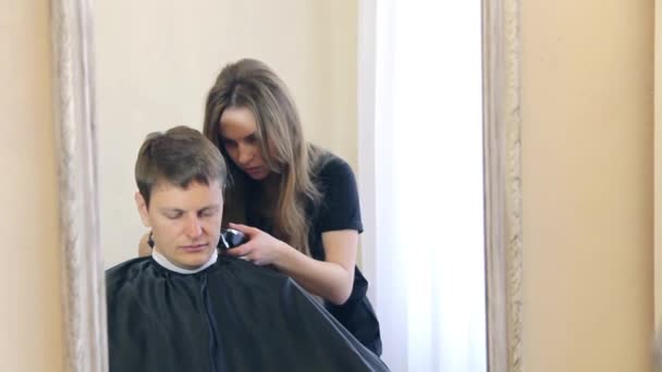 Flicka gör frisyr killen i spegeln — Stockvideo