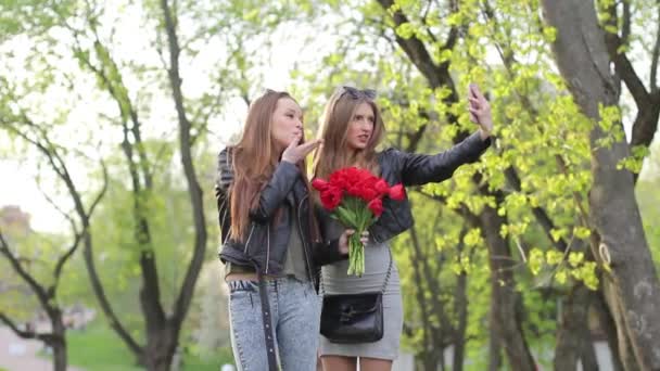 Deux belles filles font selfie sur un téléphone mobile avec des fleurs — Video