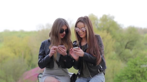 Dos chicas mensajes de texto en un dispositivo móvil — Vídeo de stock