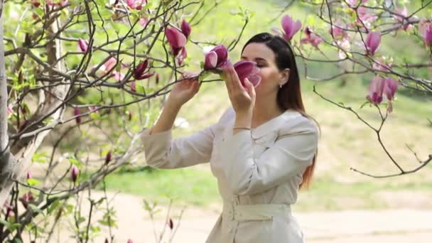 Schöne junge Brünette in einem blumigen Frühlingsgarten — Stockvideo