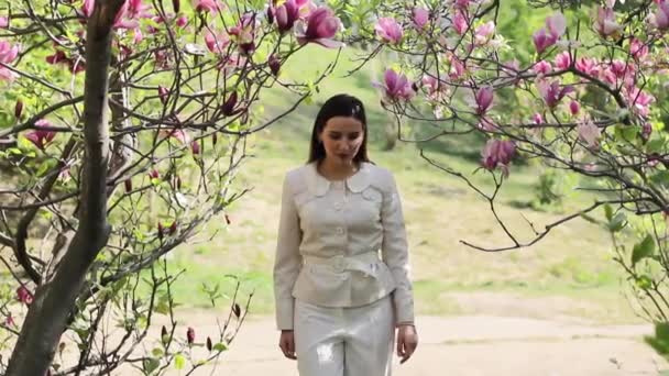 Vacker ung brunett i en blommig våren trädgård — Stockvideo