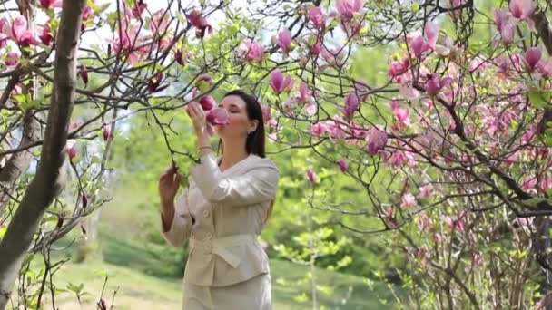 Mooie jonge brunette in een bloemrijke lentetuin — Stockvideo