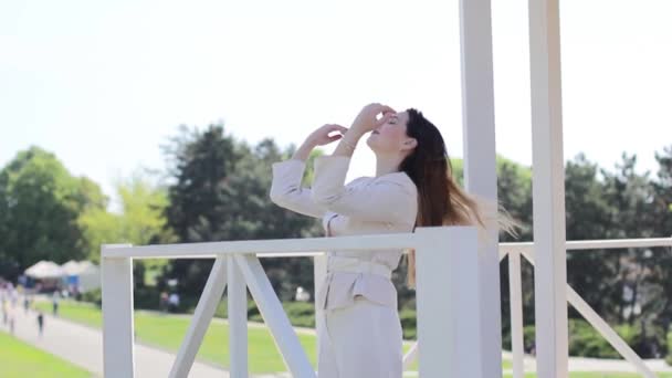 Hermosa chica endereza su cabello estar cerca barandilla al aire libre — Vídeos de Stock
