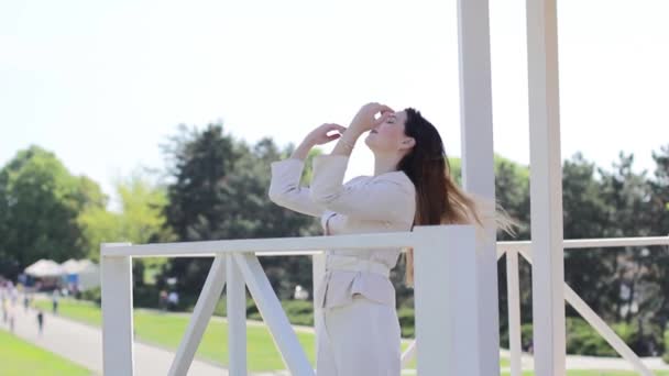 Bella ragazza raddrizza i capelli essendo vicino ringhiera all'aperto — Video Stock