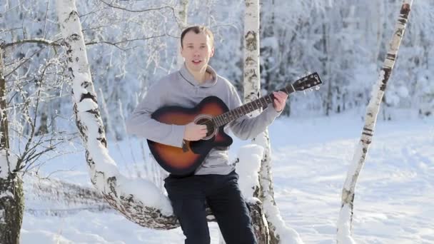 Jovem cara tocando a guitarra na floresta nevada — Vídeo de Stock