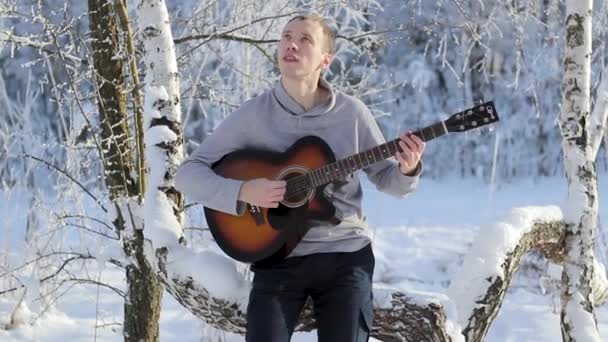 Молодий хлопець взимку грає на гітарі — стокове відео