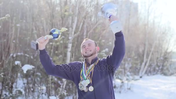 Young guy sportsman rejoices with cups and medals — Stock Video