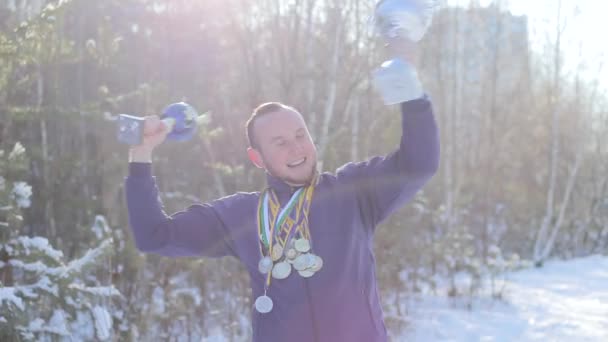 Спортсмен с кубками и медалями радуется победе — стоковое видео