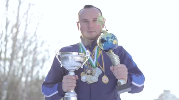 Skäggig kille med medaljer och koppar på fotboll — Stockvideo