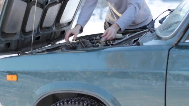 Een jonge kerel corrigeert een uitsplitsing van zijn auto — Stockvideo