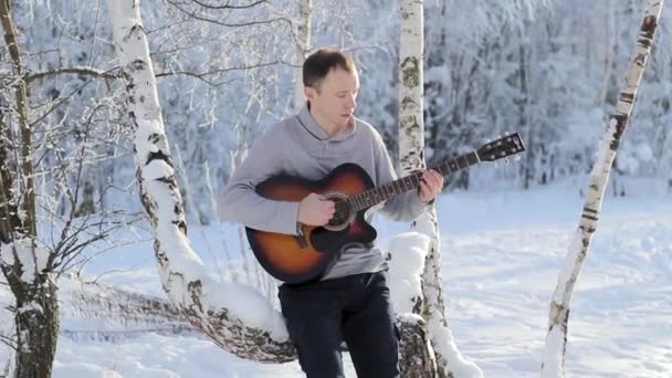 Молодий хлопець взимку грає на гітарі — стокове відео