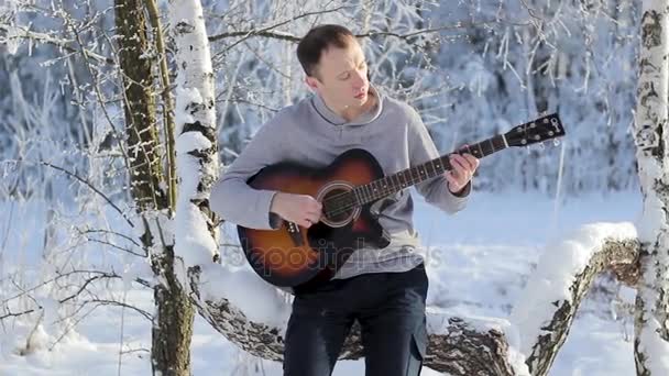 Jonge kerel in de winter spelen gitaar — Stockvideo