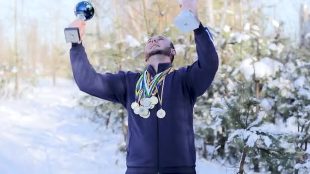 Desportista com copos e medalhas se alegra na vitória — Vídeo de Stock