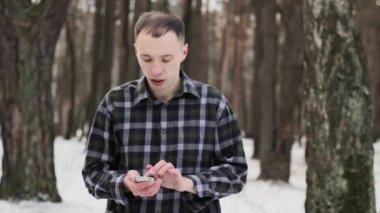 adam ormanda karla kaplı soğuk bir cep telefonu ile