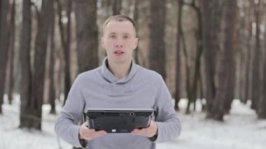 dizüstü bilgisayar ile karla kaplı ormandaki adam