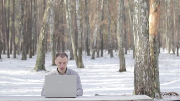 Парень в заснеженном лесу с ноутбуком — стоковое видео