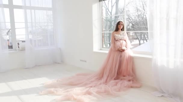 Hermosa joven embarazada en vestido largo rosa — Vídeos de Stock