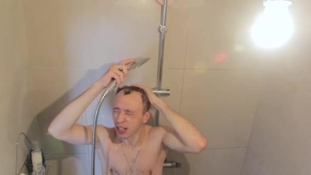 Молодой парень моется в душе — стоковое видео