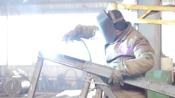 Trabalhador industrial solda uma estrutura metálica — Vídeo de Stock
