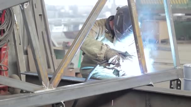 Trabalhador industrial solda uma estrutura metálica — Vídeo de Stock