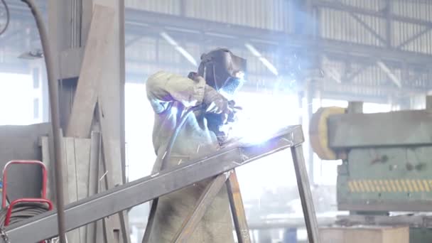 Працівник зварює металеві конструкції на заводі — стокове відео
