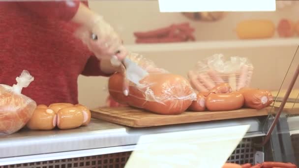 Primer plano de la mano de las carniceras mostrando salchichas en la tienda — Vídeos de Stock