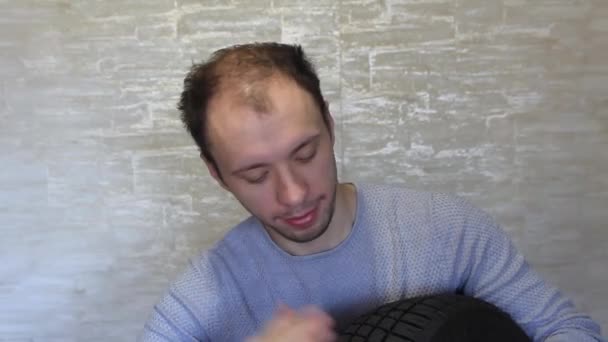 Un fou avec un pneu d'une voiture dans ses mains s'amuse. — Video