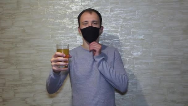 자기 고립에 대한 코로나 바이러스에 걸렸을 때 맥주 한 잔하고 마스크를 쓴 남자의 초상화. 코로나, 코로나 바이러스에 근접 한 남자. — 비디오