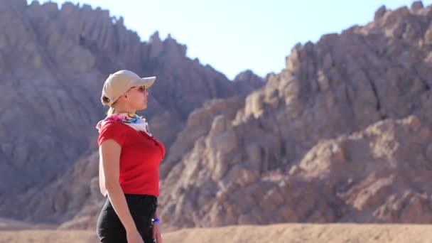 Portrait d'une fille dans le désert près des montagnes en lunettes de soleil. — Video