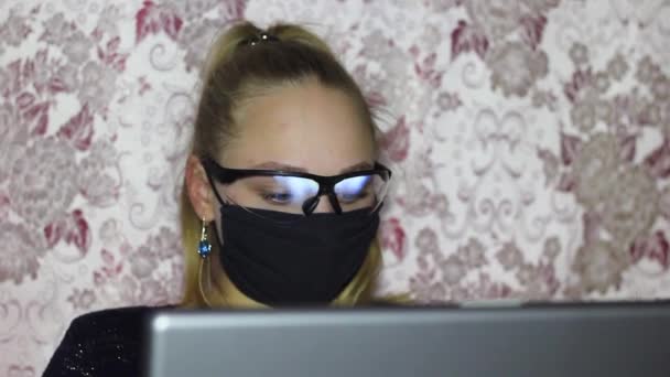 Wolna strzelanka pracuje w laptopie podczas epidemii koronowirusa w masce medycznej i okularach. — Wideo stockowe