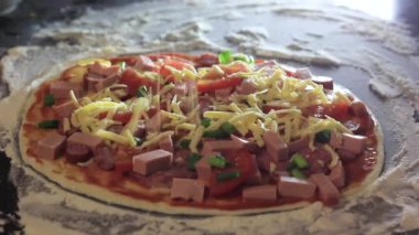 Kesim masasında pişirmek için malzemeli pizza. Peynir ekleniyor.