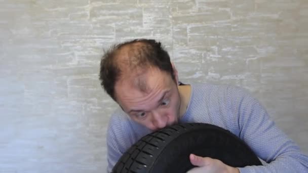 A crazy guy with a tire from a car in his hands is having fun. — Stock Video