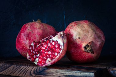 Siyah zemin üzerinde lezzetli ve olgun nar, bir kesme tahtası üzerinde, rustik tarzda