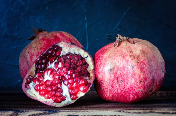 Granatapfel, köstliche und reife Früchte auf schwarzem Hintergrund, Nahaufnahme in Scheiben geschnitten — Stockfoto