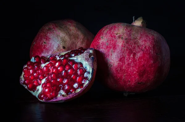 Grenades de fruits très savoureuses, sucrées et mûres sur fond noir, sur une planche à découper, style rustique — Photo