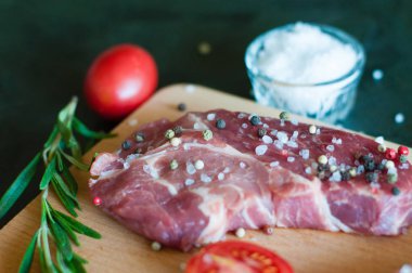 Biber ve tuz serpilmiş çiğ domuz eti, doğranmış domates ve biberiye pişirme süreci.